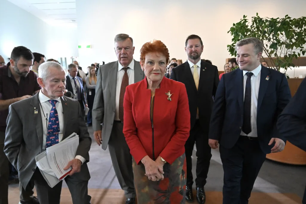 Pauline Hanson and Malcolm Roberts walking through a hallway with colleagues